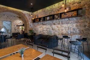Un restaurante acogedor con paredes de piedra, mesas de madera y un sofá de color oscuro.
