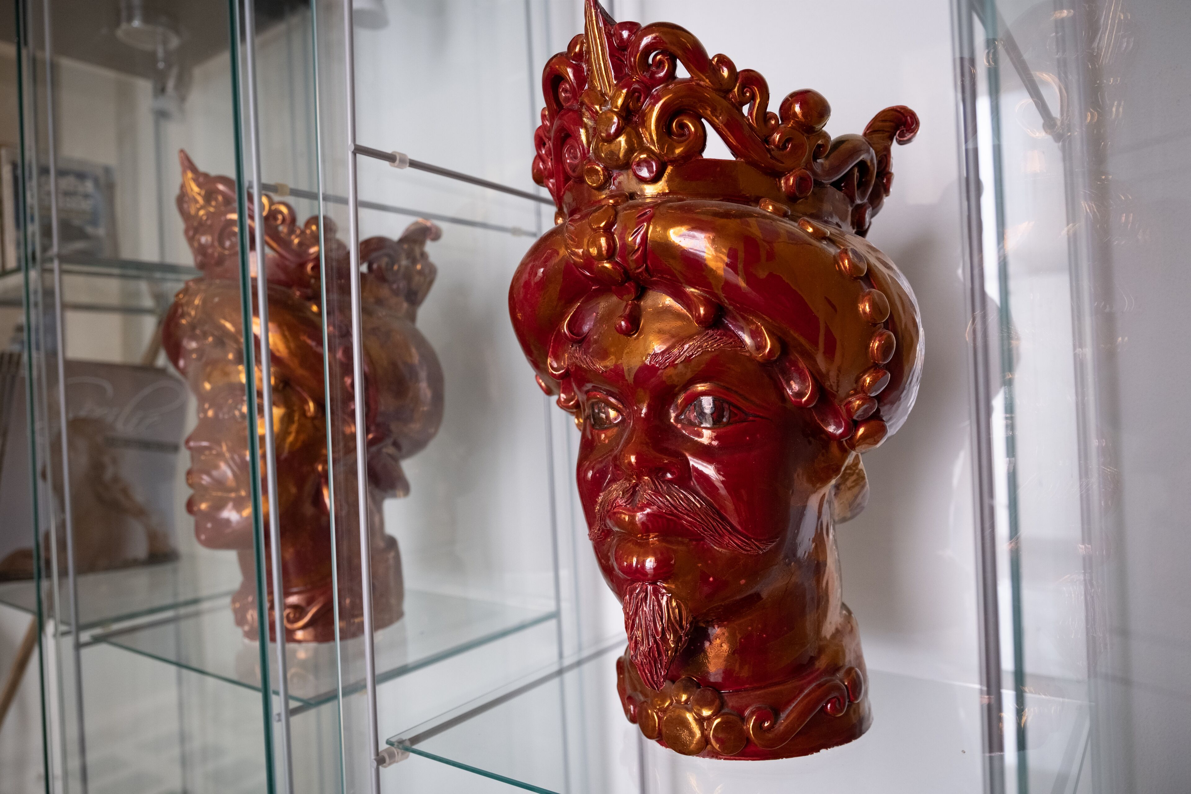 Une vitrine en verre contenant un objet décoratif aux couleurs rouge et or.