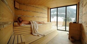 A wooden sauna with a bench, a large window, and a view of mountains. - Alpenlife Hotel Someda (Moena)