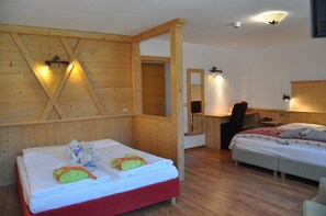 Ein Zimmer mit Holzboden, einem Bett mit rotem Gestell, einem Schreibtisch mit Stuhl und einem Spiegel an der Wand.