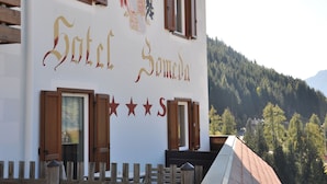 A building with the sign "Hotel Sameda" and a coat of arms. There are wooden shutters on the windows and a wooden fence in front. - Alpenlife Hotel Someda (Moena)