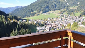 A scenic view of a town nestled in a valley with mountains in the background. - Alpenlife Hotel Someda (Moena)