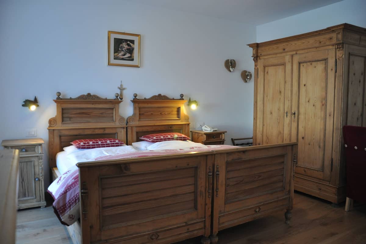 Een slaapkamer met een houten bed, nachtkastje, kledingkast en een wandlamp.