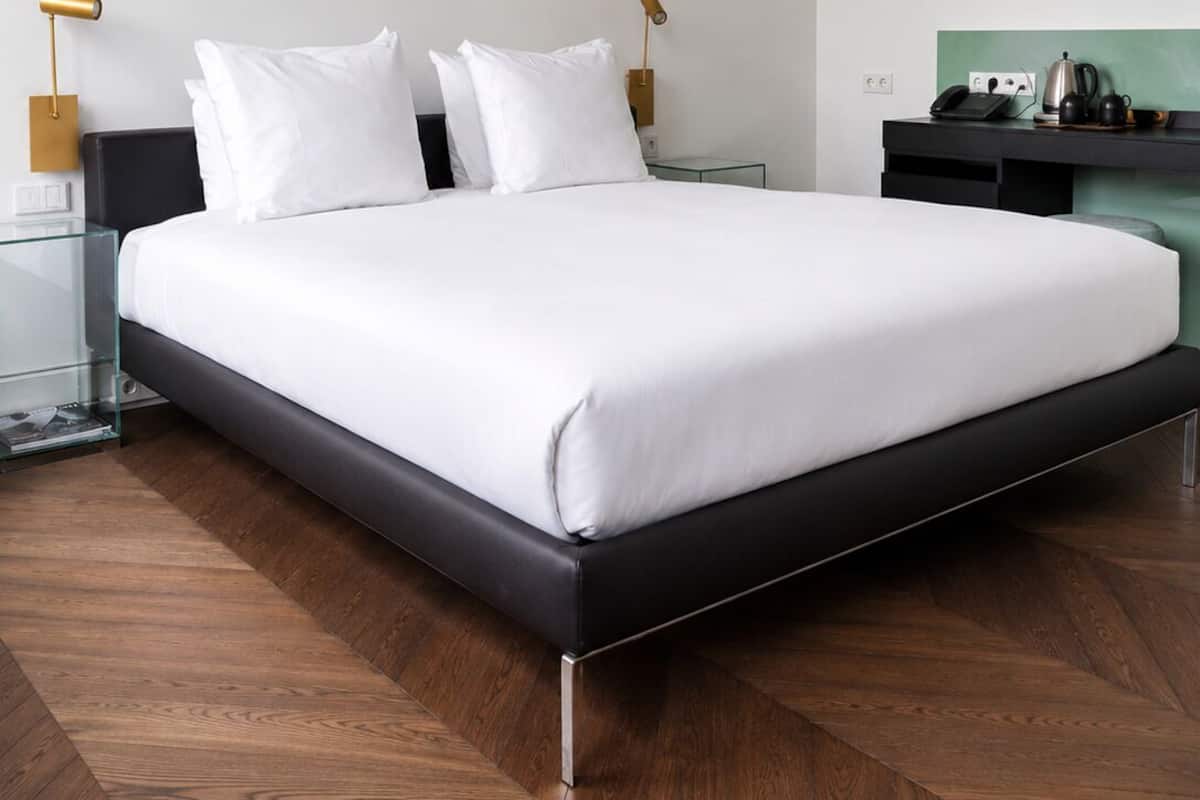 Ein modernes Schlafzimmer mit einem großen Bett, Nachttischen, einem Schreibtisch und einer grünen Wand.