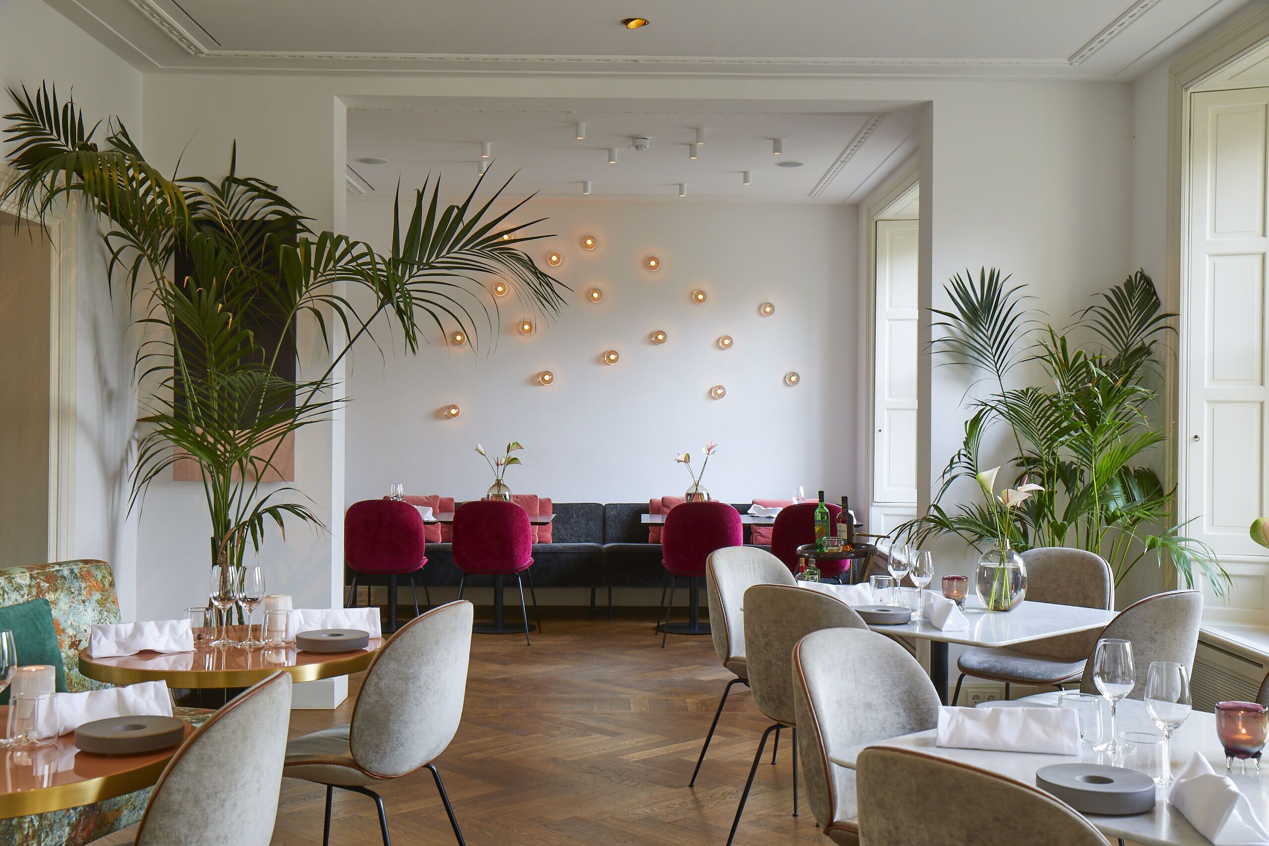 A restaurant with round tables, chairs, and potted plants.
