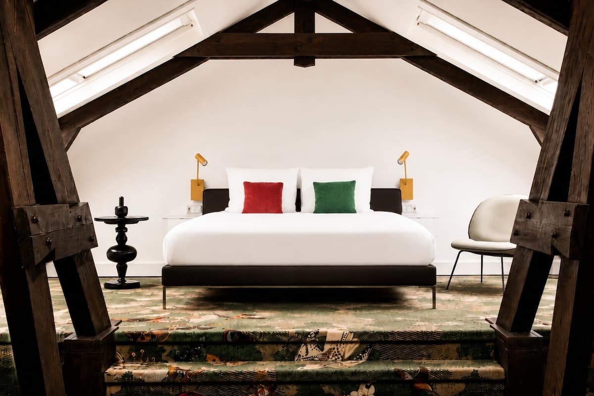 Ein Schlafzimmer mit einem großen Bett, einem kleinen Tisch, zwei Nachttischlampen und einem Sessel.