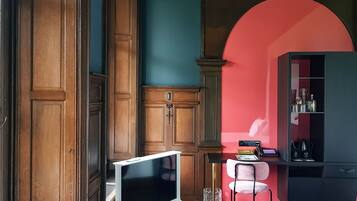 Una habitación con paneles de madera, un televisor de pantalla plana, una silla rosa y un arco rojo.