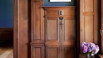 A room with a wooden cabinet, a framed artwork, and a vase with flowers.