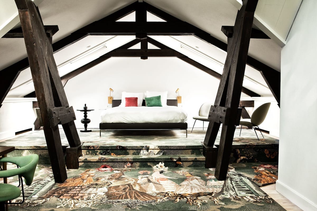 Ein Schlafzimmer mit einem Bett, einem Sessel, einem Tisch und einem großen Fenster.