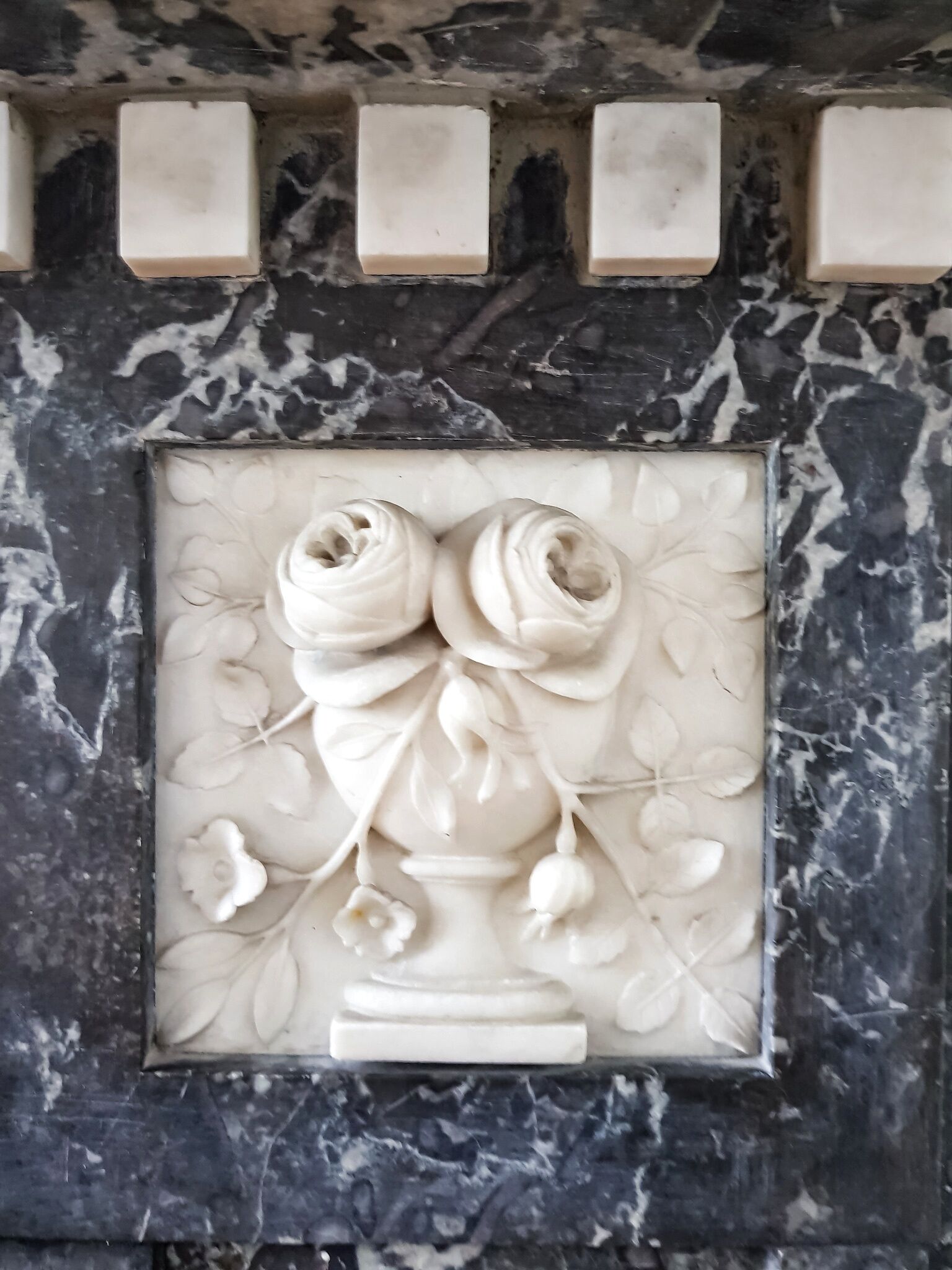 A marble fireplace with a floral relief sculpture.