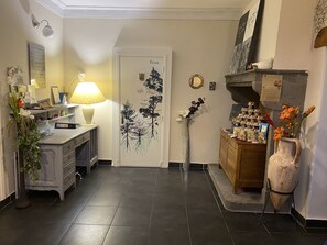 A hallway with a desk, lamp, and decorative items. There is a door with a 'Privé' sign, a mirror, and a vase with flowers. - A l'Aube des Volcans (Charbonnières-les-Vieilles)