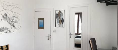 Une chambre à coucher avec un lit, un bureau, une chaise, une télévision et une porte dotée d’un miroir.