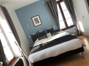 A bedroom with a bed, a window with curtains, a radiator, and a picture on the wall. - A l'Aube des Volcans (Charbonnières-les-Vieilles)