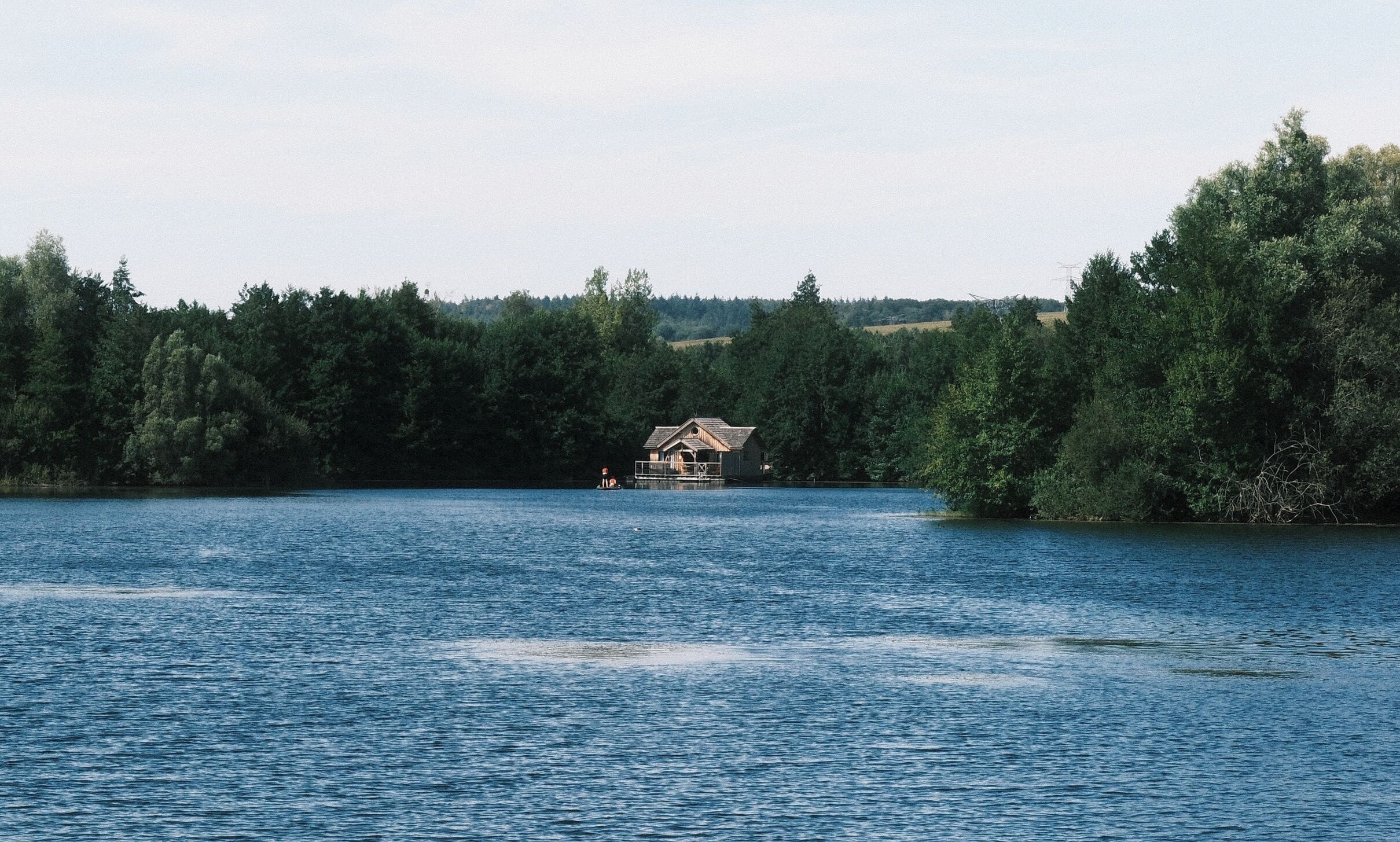 A cabin on a lake surrounded by dense forest.
