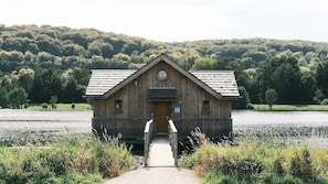 A wooden cabin with a front door, a small window, and a wooden staircase leading up to it.