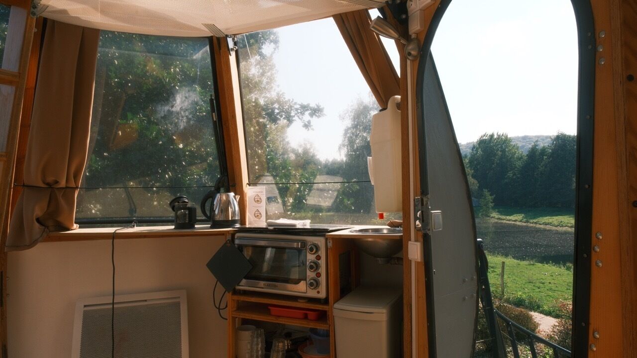 Een compact keuken met een magnetron, waterkoker en een raam met uitzicht op een landelijk gebied.