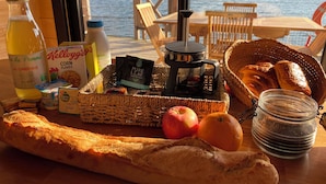 Et morgenbord med brød, frugt og drikkevarer med udsigt til en sø.
