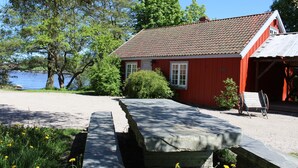 A red building with a tiled roof, a bench, and a small wheelbarrow. - Magasinet (Fredrikstad)