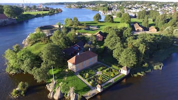 Luftaufnahme eines Anwesens an einem Flussufer mit einem großen Haus, einem Garten und einem Steg.