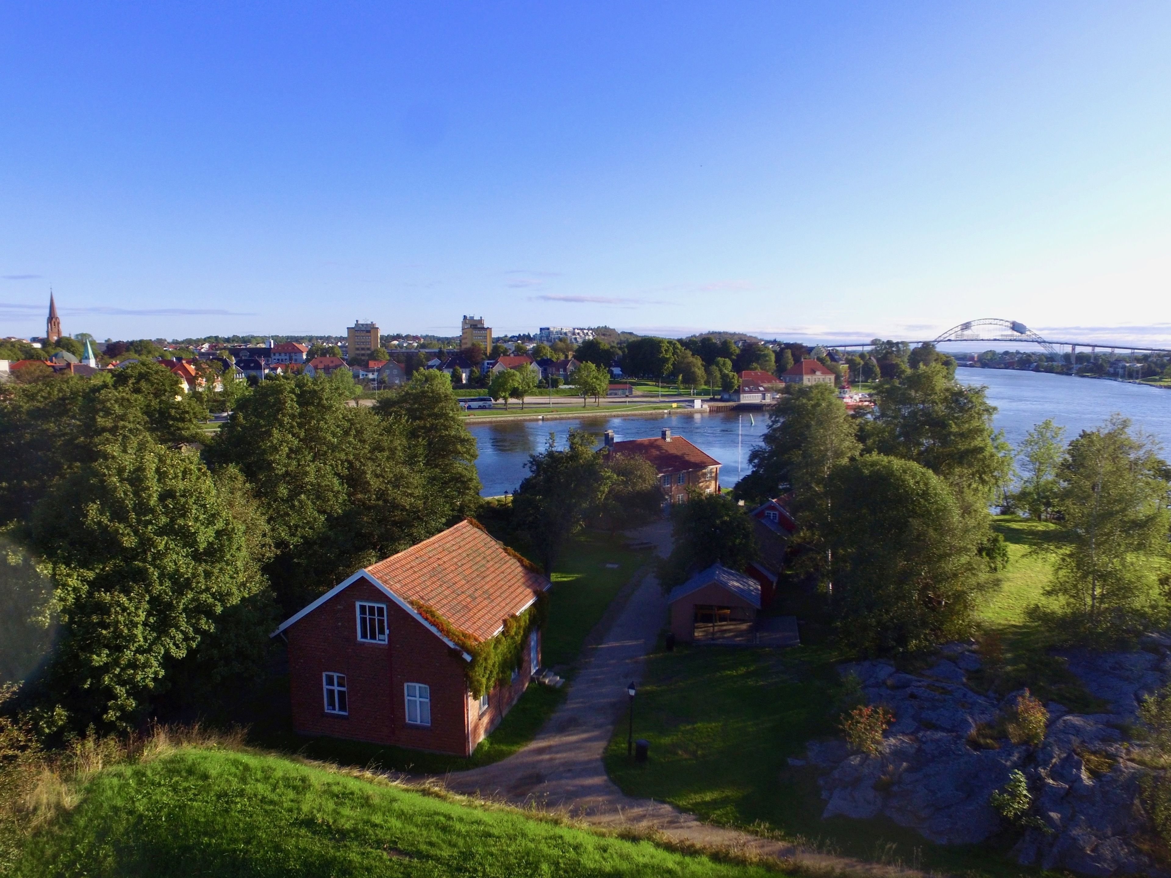 A riverside town with a prominent church spire, a bridge, and a mix of residential and commercial buildings.