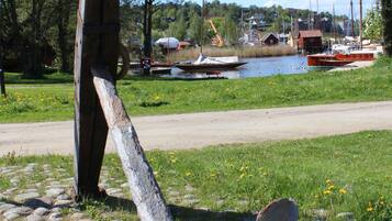 A large anchor sculpture in a grassy area with boats in the background.