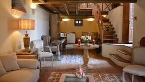 A cozy interior with a wooden ceiling, a dining area with a table and chairs, a staircase, and a patterned floor. - Archontiko Chioti (South Kynouria)