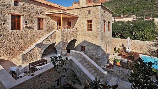 A stone building with a balcony, outdoor seating, and a pool. - Archontiko Chioti (South Kynouria)