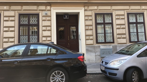 A building with a brown door marked with the number 3, two parked cars, and a window with decorative glass. - Heart of Vienna Harmoniegasse (Vienna)