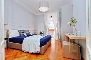 A modern bedroom with a bed, bedside tables, a desk, and a view of the balcony. - JOIVY Austere Elegance (Milan)
