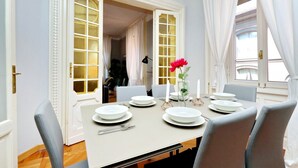 A dining area with a table set for four, white plates, a vase with a single flower, and a modern lamp. - JOIVY Austere Elegance (Milan)
