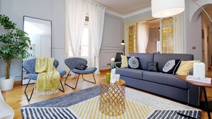 A modern living room with a grey sofa, two armchairs, a patterned rug, and a potted plant. - JOIVY Austere Elegance (Milan)