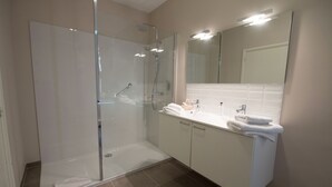 A modern bathroom with a glass-enclosed shower, a white vanity with a mirror, and a tiled floor. - Hotel Keravic (Kasterlee)