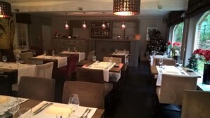 A restaurant with multiple tables set for dining, a bar area, and a Christmas tree. - Hotel Keravic (Kasterlee)