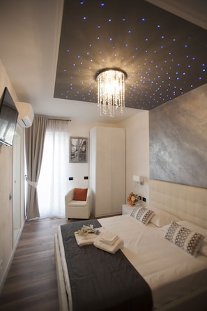 A modern bedroom with a large bed, a chandelier, a wardrobe, and a painting on the wall. - My Way (La Spezia)