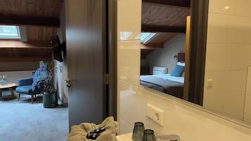 Un baño con un espejo grande, un lavamanos y un perchero para toallas.