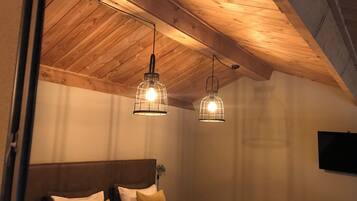 A bedroom with a wooden ceiling, a bed with multiple pillows, and two hanging light fixtures.