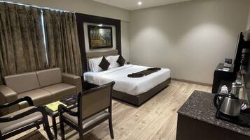 Quarto de hotel moderno com cama, sofá, uma mesinha e máquina de café.