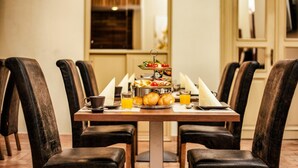 Una mesa de desayuno con una bandeja escalonada de fruta y queso, croissants, jugo de naranja y una taza de café.