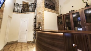 Un área de recepción con un arco de piedra, un mostrador de madera y un televisor montado en la pared.