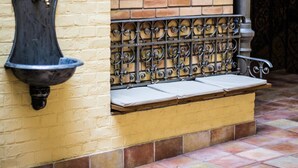 Un banco con respaldo de metal y un lavamanos fijado a la pared.