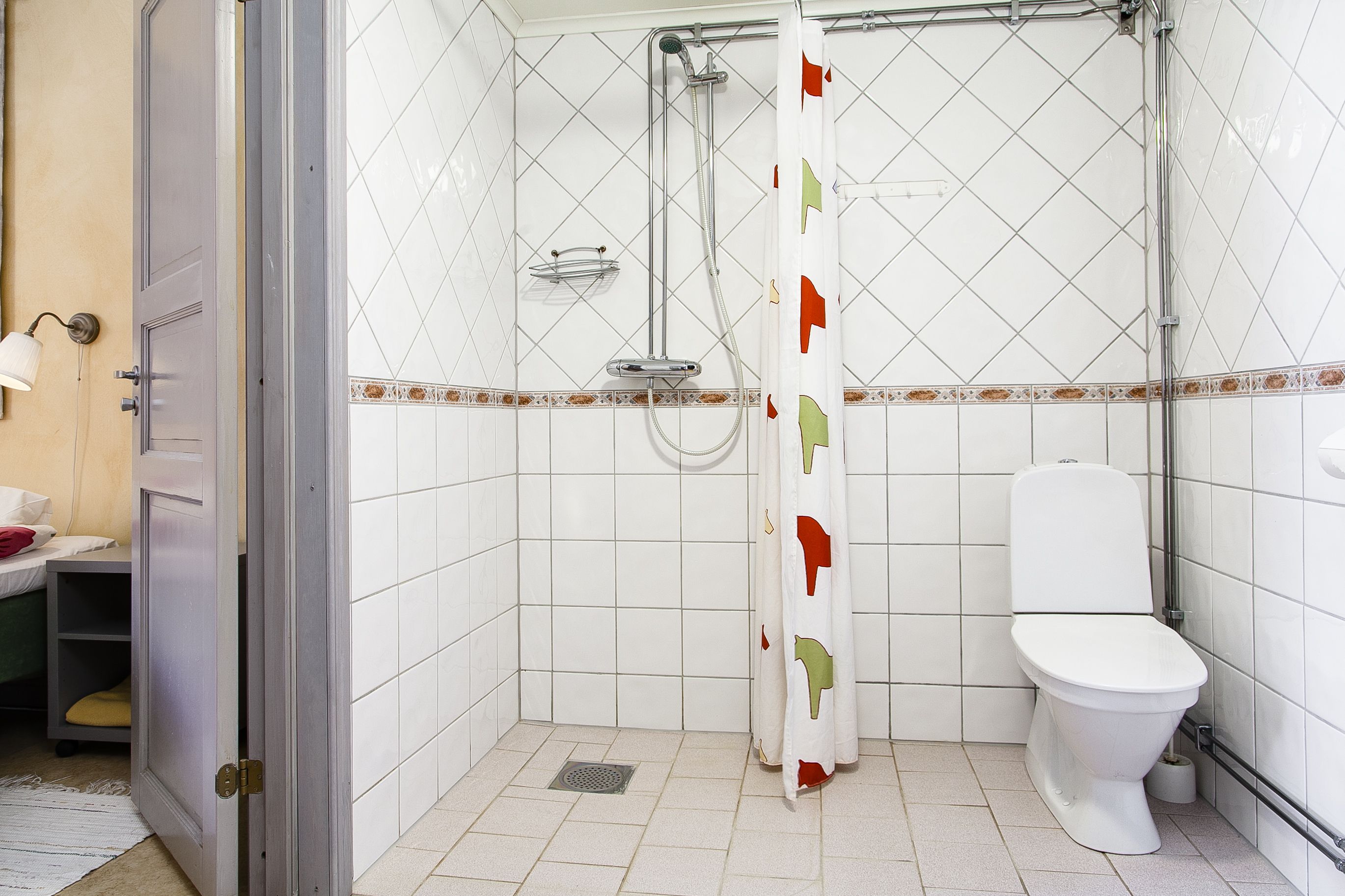 Un baño pequeño con ducha, inodoro y un perchero para toallas.