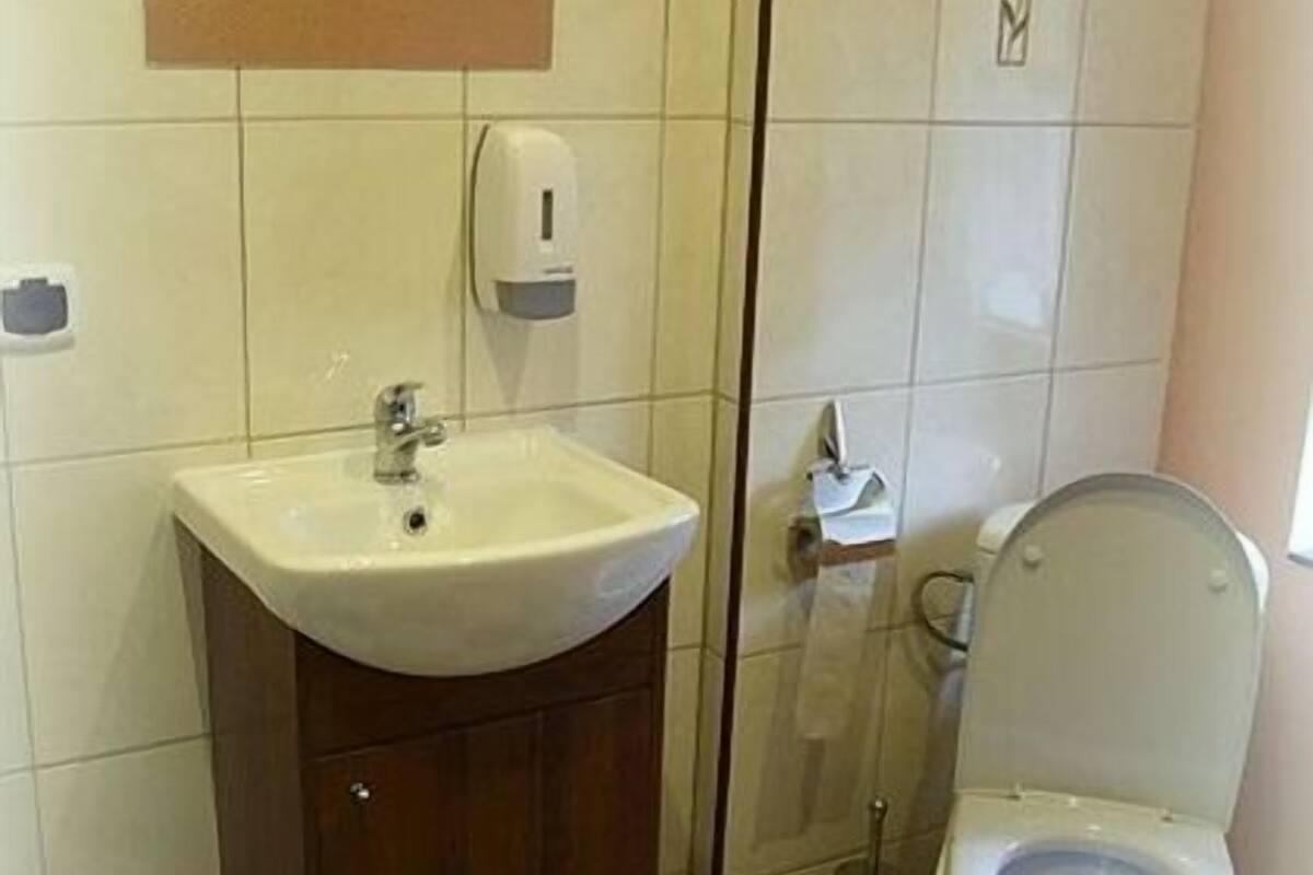 A bathroom with a sink, toilet, and hand dryer.