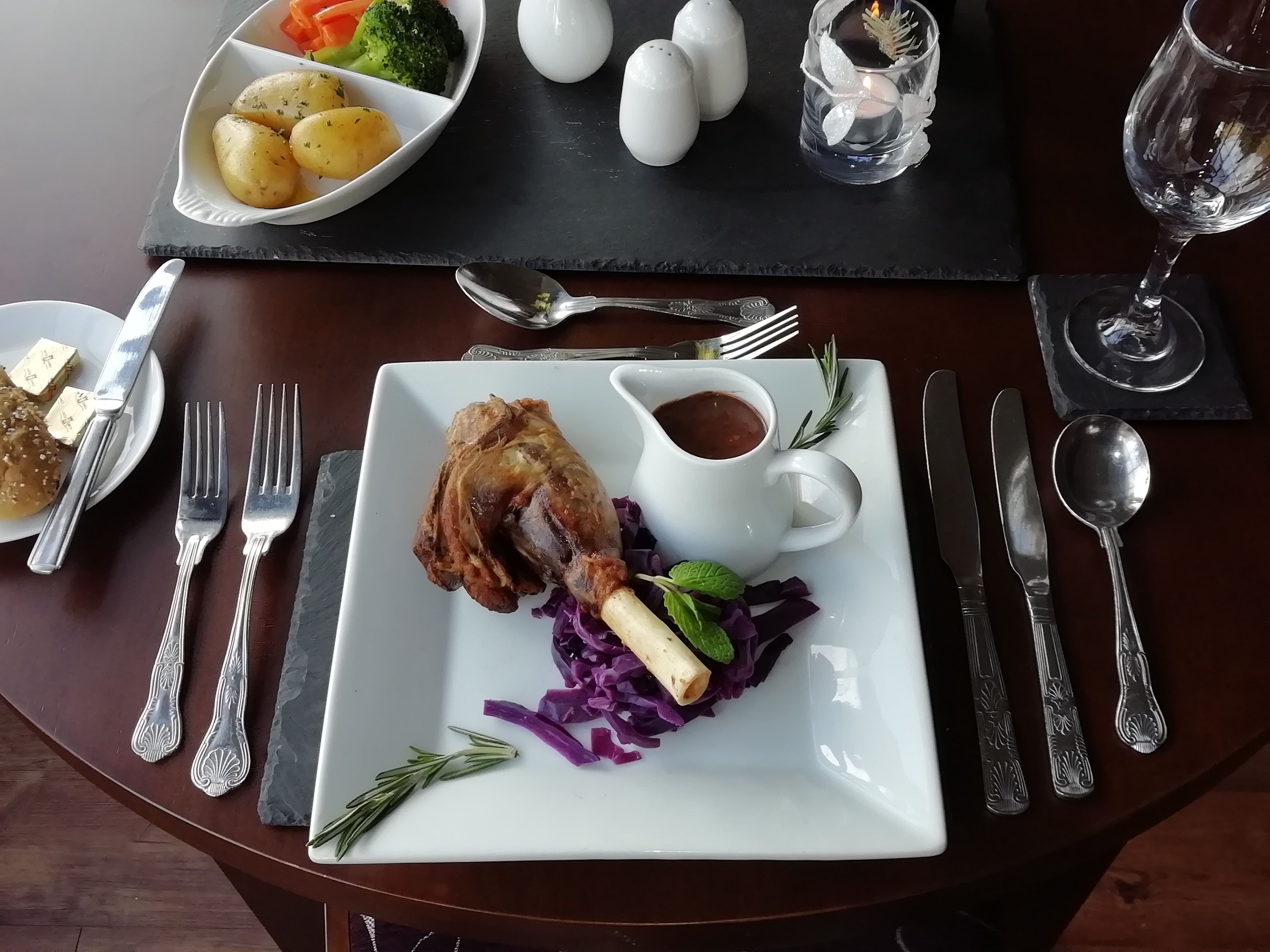 A dining table with a plate of food, cutlery, and a glass of water.