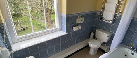 Un baño con ventana, inodoro, lavamanos y bañera.