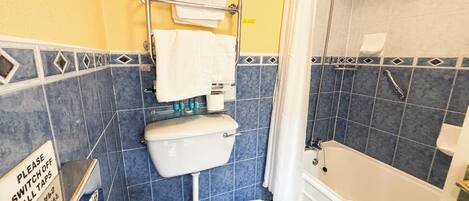 A bathroom with a toilet, a shower, and a bathtub. There is a sign on the wall that says "Please switch off all taps."