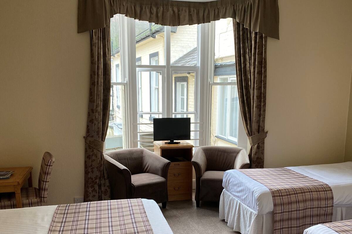 A hotel room with two beds, a TV, a small table, and a chair.