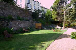 A garden with a stone wall, a wooden bench, and a lawn.