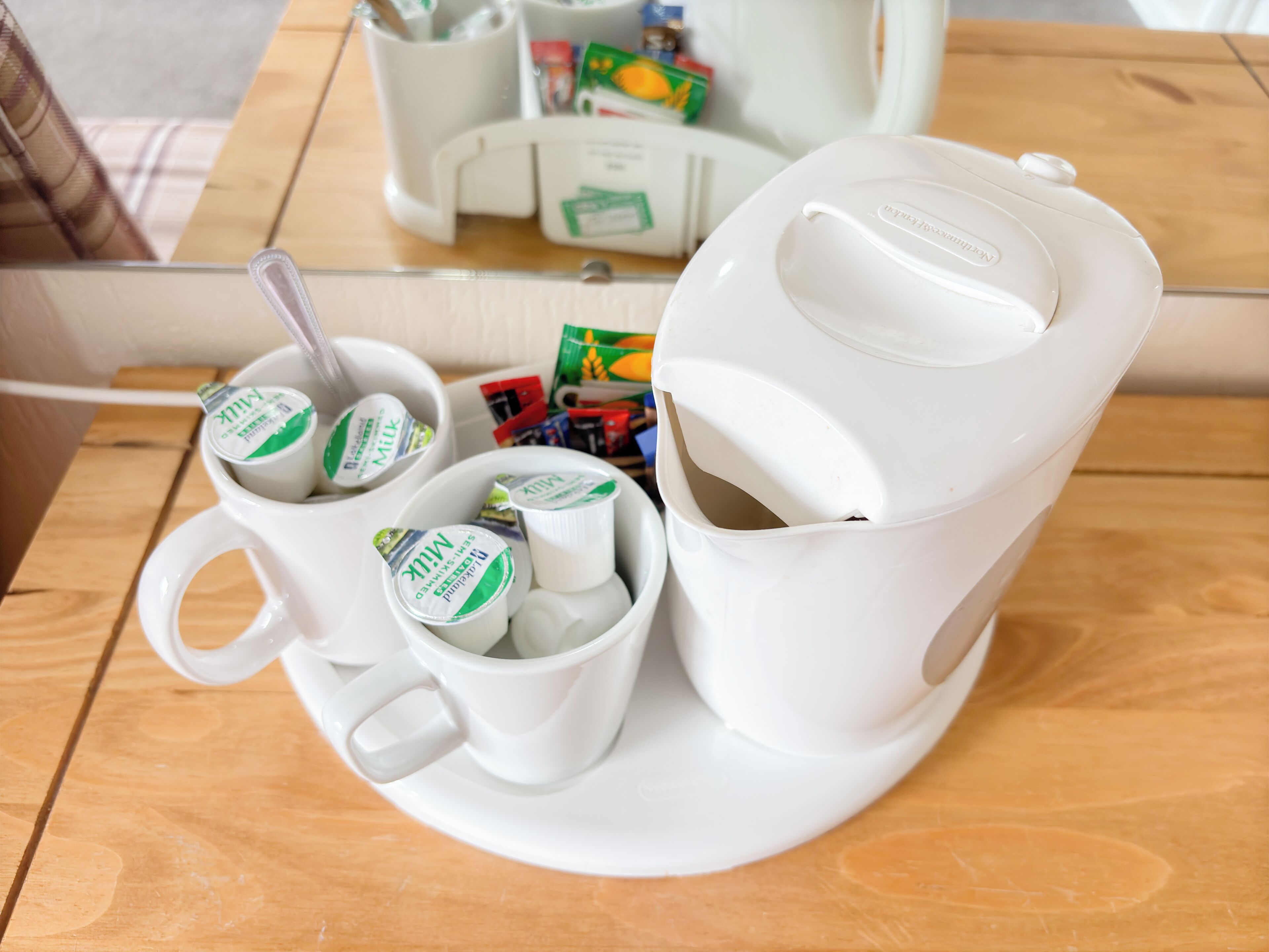 A white coffee maker with a milk frother on a wooden table.