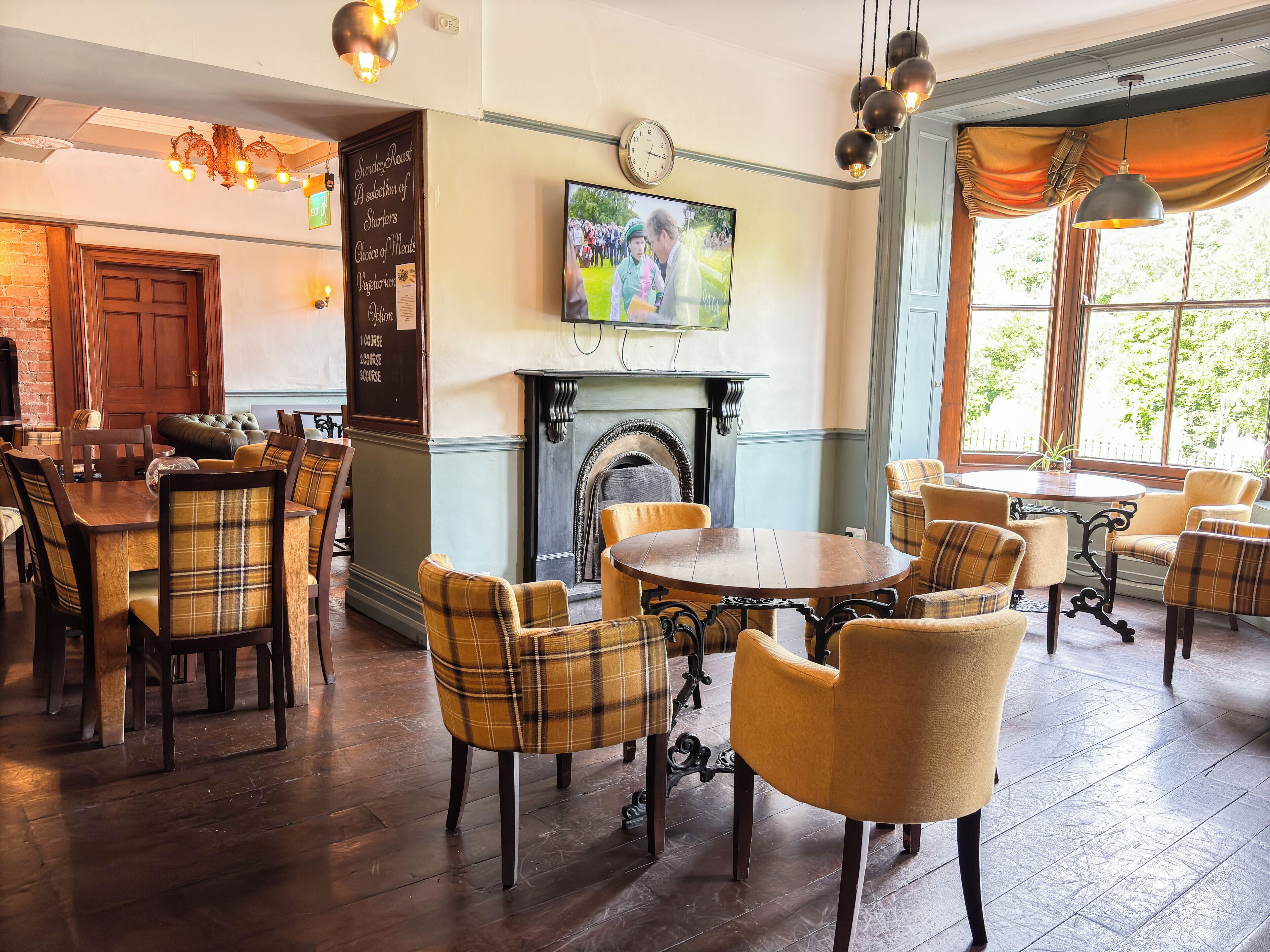 A dining area with wooden tables and chairs, a fireplace, and a television mounted on the wall.