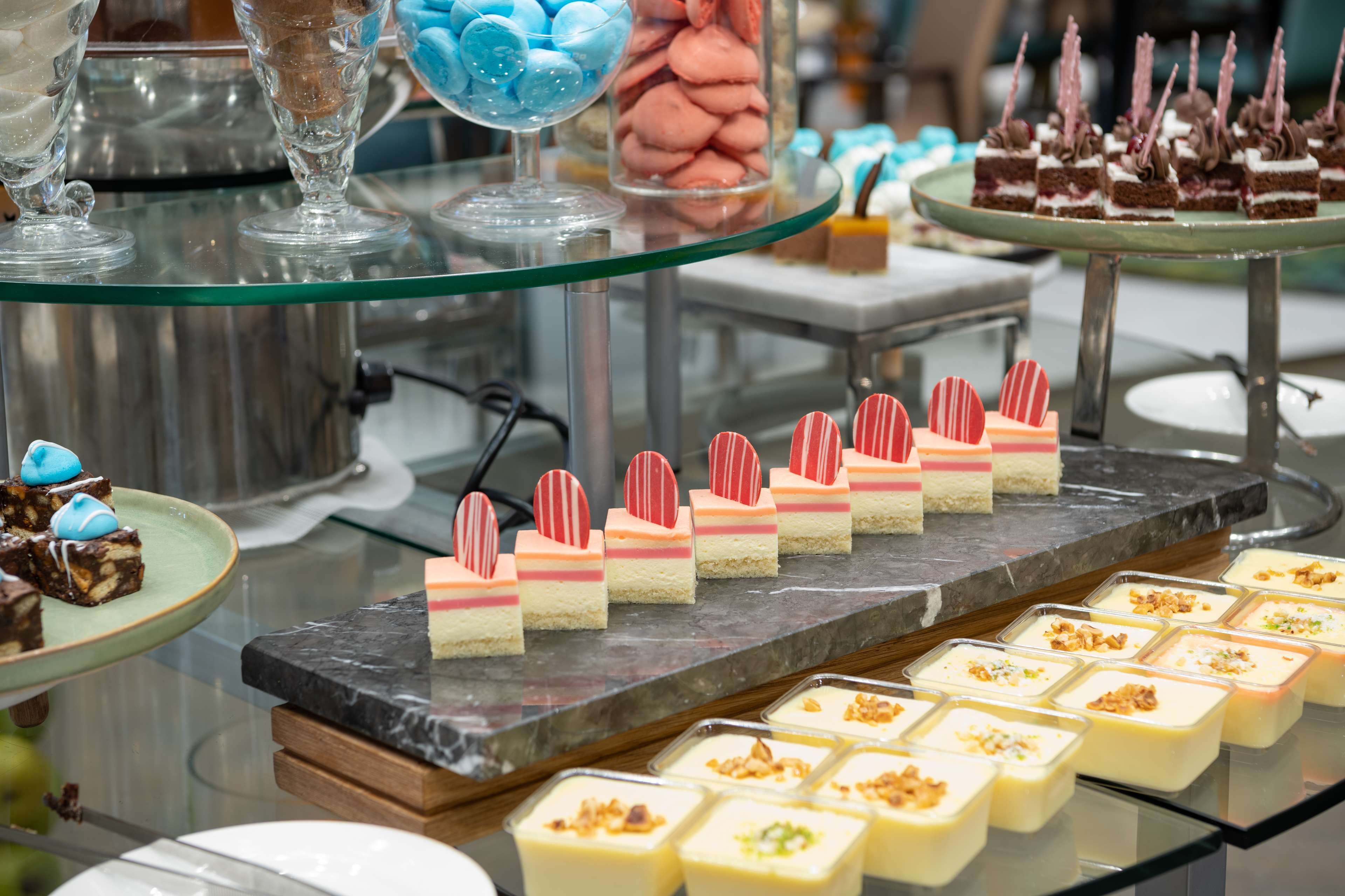A variety of desserts on display, including macarons, layered cakes, and other sweet treats.
